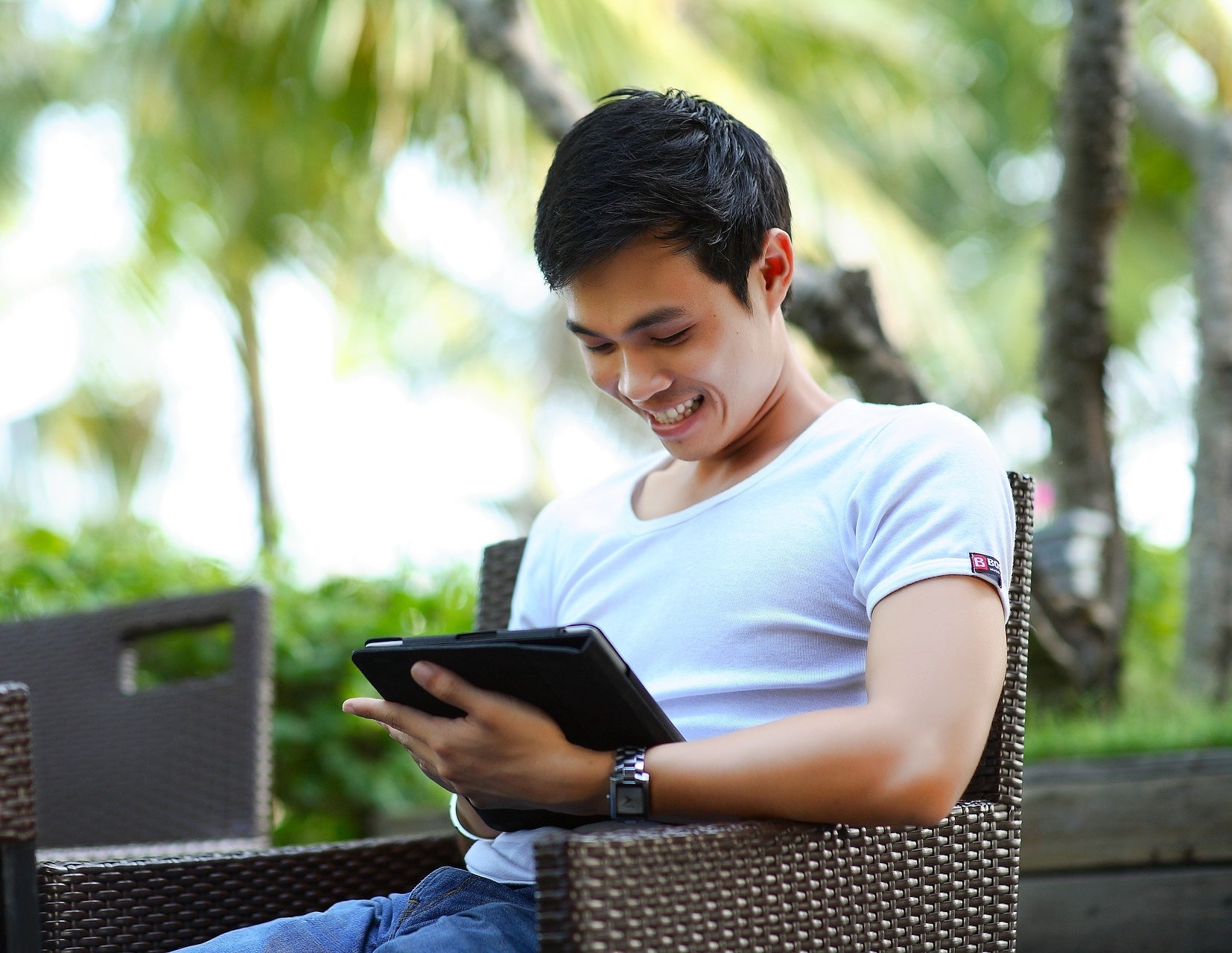 Man sitting and using a tablet outdoors in a garden setting